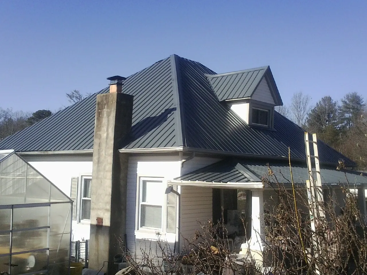 Dark blue standing seam metal roof on a white farmhouse with dormer — Slate & Tile Roof Repair by Roofing Brothers in Lilliwaup