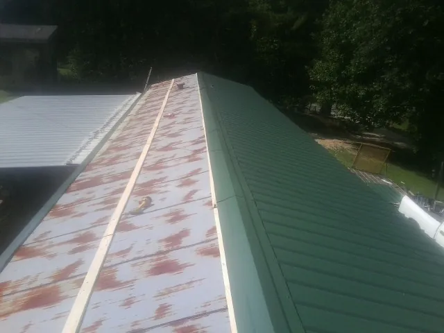 Old rusted panels beside newly installed green metal roofing — Wind Damage Roof Repair by Roofing Brothers in Lilliwaup