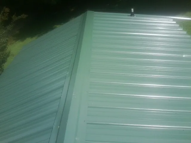 New green metal panels meeting at the ridge of a roof — Flat Roof Repair work by our crew in Lilliwaup