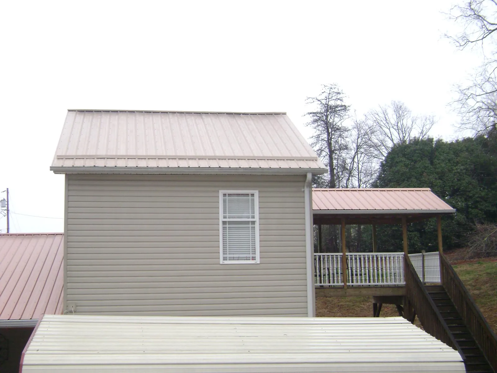 Tan metal roofs on a two story addition and attached porch, from a Roof Replacement job in Lilliwaup