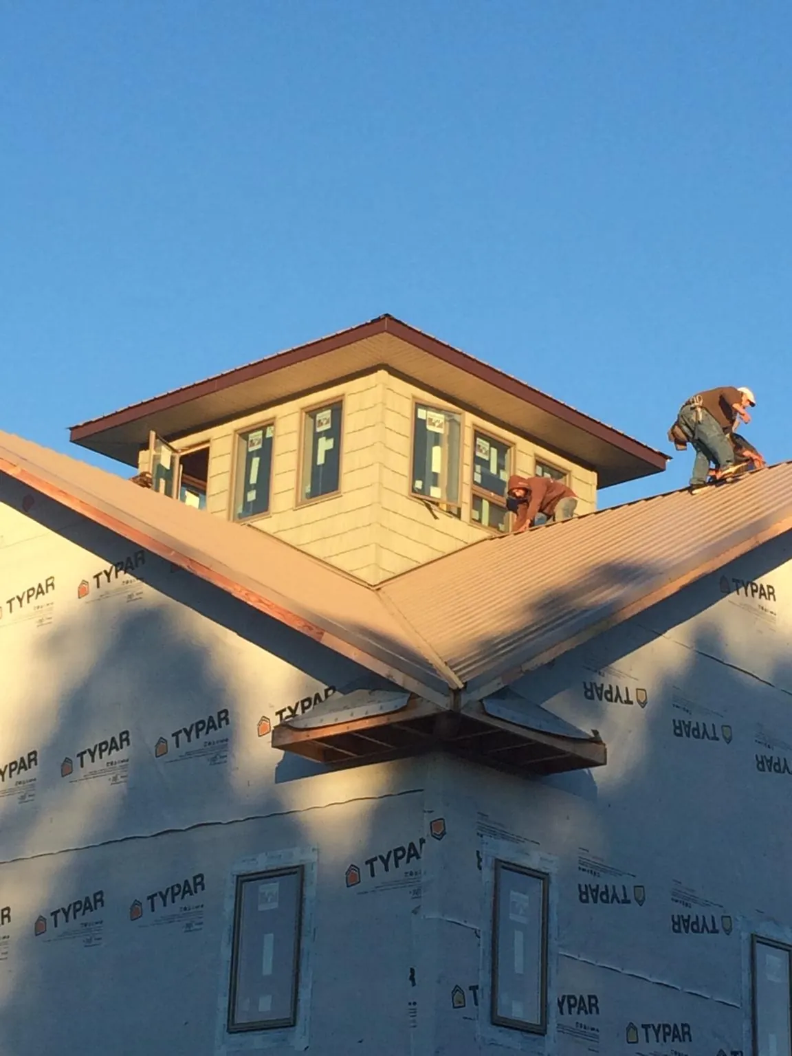 Roofers working around a rooftop cupola on a new metal roof at sunset — Roof Waterproofing in Lilliwaup by Roofing Brothers